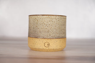 Birch pattern candle on light brown speckled ceramic vessel, front view