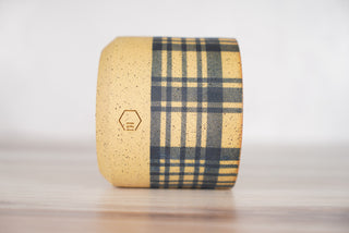 Blue plaid pattern candle on light brown speckled ceramic vessel, third view