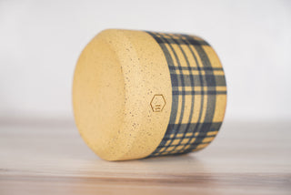 Blue plaid pattern candle on light brown speckled ceramic vessel, fourth view