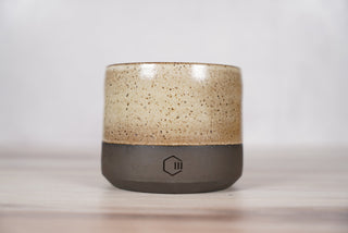 Embers speckled beige and brown glaze candle on dark brown ceramic vessel, front view