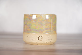 Mother of pearl glaze on light brown speckled ceramic candle vessel, front view