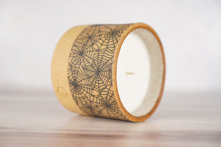 Spiderweb pattern candle on light brown speckled ceramic vessel, second view