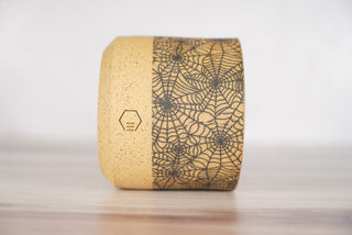 Spiderweb pattern candle on light brown speckled ceramic vessel, third view