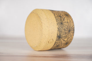 Spiderweb pattern candle on light brown speckled ceramic vessel, fourth view