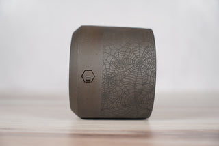 Black spiderweb pattern candle on dark brown speckled ceramic vessel, third view