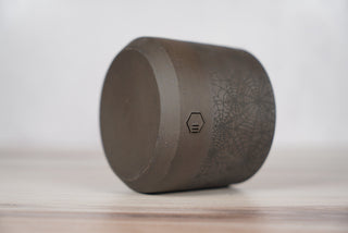 Black spiderweb pattern candle on dark brown speckled ceramic vessel, fourth view