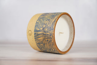 Blue topographic map pattern candle on light brown speckled ceramic vessel, second view