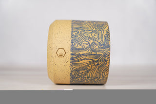 Blue topographic map pattern candle on light brown speckled ceramic vessel, third view
