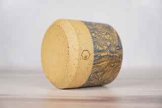 Blue topographic map pattern candle on light brown speckled ceramic vessel, fourth view